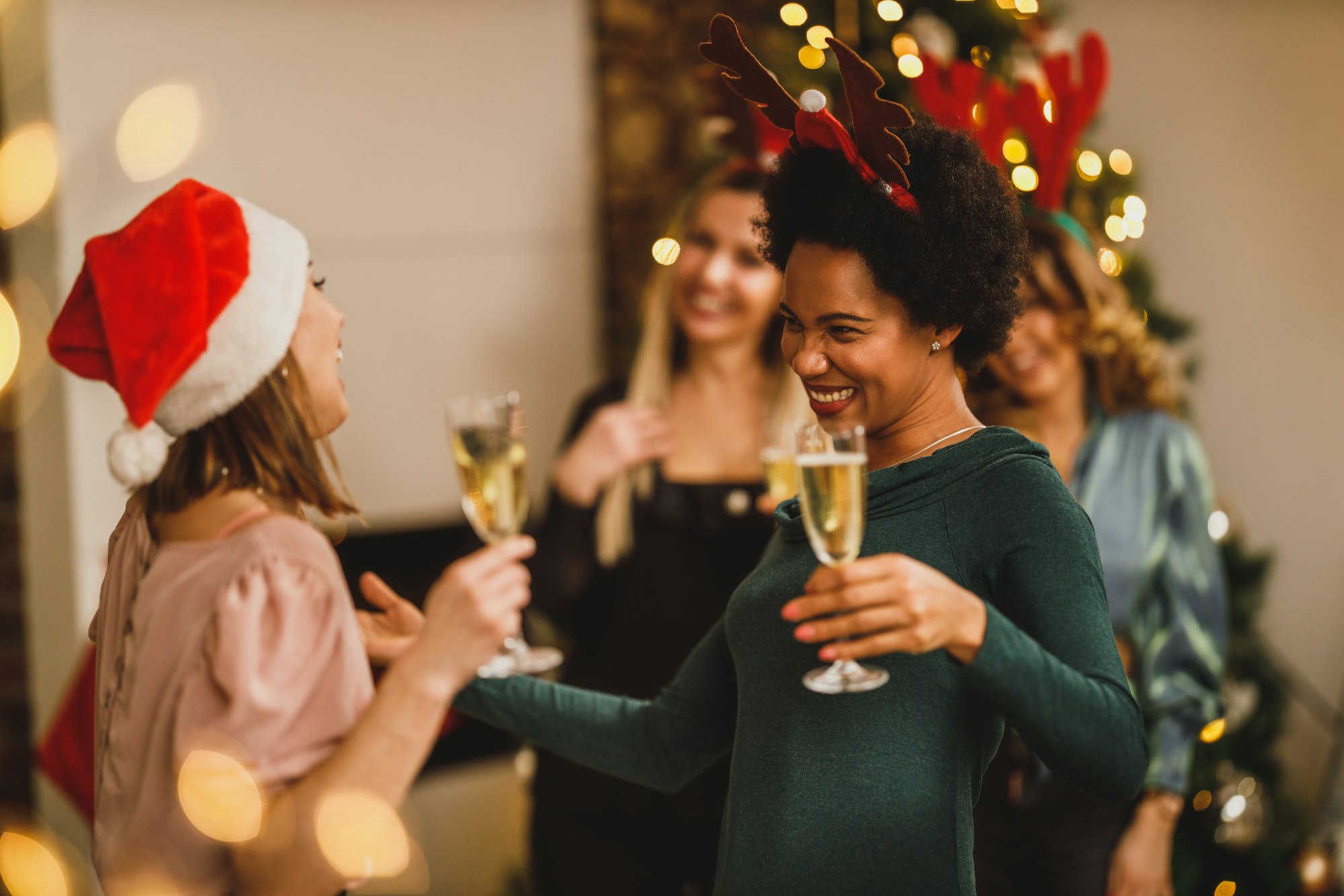 Female Friends Make Toast With Champagne As They Celebrate Christmas At Home Party